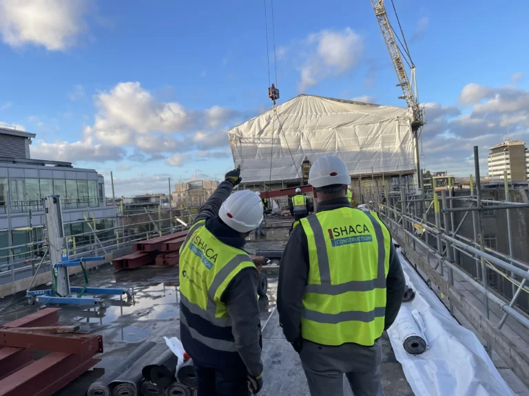 Shaca Workers Pointing at a recenlty built Construction Site showcasing what SHACA is about